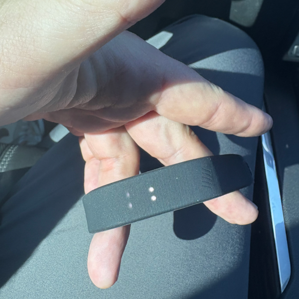 Person holding a black fitness tracker in a car interior